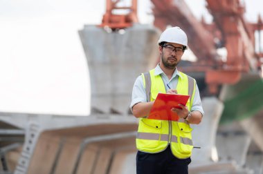 An Asian male engineer works at a motorway bridge construction site,Civil worker inspecting work on crossing construction,Supervisor working at high-speed railway construction site clipart