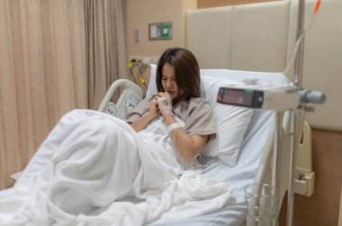 Asyalı kadın hasta ve hastanede tedavi görüyor, doktorun damar içi ilaç vermesini bekliyor, bir hemşire ateşimi ölçmek ve kan basıncımı ölçmek için geldi..