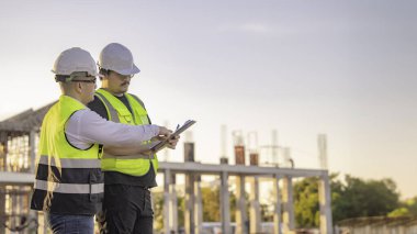 Tayland 'da büyük bir inşaat projesinin şantiyesinde çalışan iki Asyalı mühendis şantiyede fazla mesai, şantiyede çalışan bir mühendis diski.
