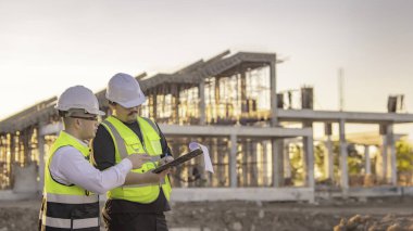 Tayland 'da büyük bir inşaat projesinin şantiyesinde çalışan iki Asyalı mühendis şantiyede fazla mesai, şantiyede çalışan bir mühendis diski.