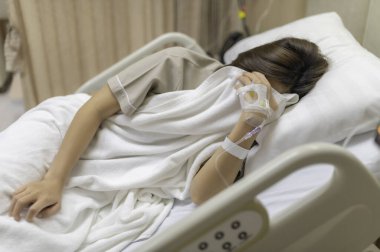 Asyalı kadın hasta ve hastanede tedavi görüyor, doktorun damar içi ilaç vermesini bekliyor, bir hemşire ateşimi ölçmek ve kan basıncımı ölçmek için geldi..