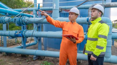 Mühendis ve teknisyen bakımı, su pompası ve basınç göstergesi, su tedarikçisinin teknik verilerini kontrol ediyor.