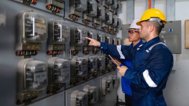 Elektrik mühendisleri ve teknisyenleri endüstriyel kontrol odalarındaki elektrik sistemi arızalarını çözmek için birlikte çalışıyorlar..