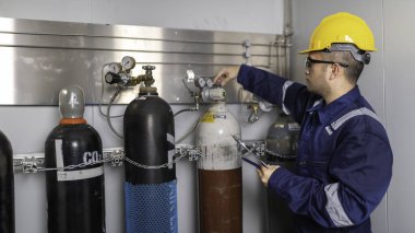 Tayland 'da, ameliyathanede çalışan Asyalı mühendis kask takıyor özenle ve sabırla çalışıyor, hidrojen tankının kapakçık düzenleyicisini kontrol ediyor..