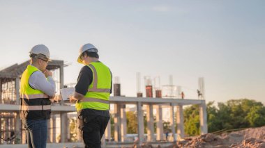 Tayland 'da büyük bir inşaat projesinin şantiyesinde çalışan iki Asyalı mühendis şantiyede fazla mesai, şantiyede çalışan bir mühendis diski.