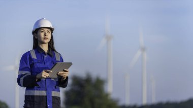 Taylandlı iki mühendis rüzgar türbini çiftliği güç jeneratörü istasyonunda çalışıyor ve raporları tutuyor. Teknisyen erkek ve kadın iş hakkında tartışıyorlar.