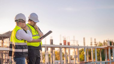 Tayland 'da büyük bir inşaat projesinin şantiyesinde çalışan iki Asyalı mühendis şantiyede fazla mesai, şantiyede çalışan bir mühendis diski.