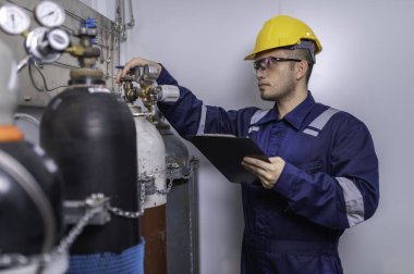 Tayland 'da, ameliyathanede çalışan Asyalı mühendis kask takıyor özenle ve sabırla çalışıyor, hidrojen tankının kapakçık düzenleyicisini kontrol ediyor..