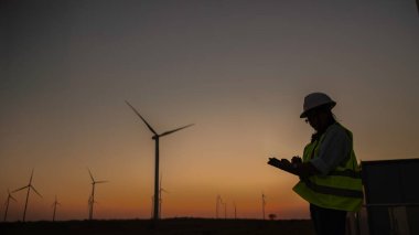 Kadın mühendis, Tayland 'daki dağda rüzgar türbini tarım güç jeneratörü istasyonunda çalışıyor ve raporu tutuyor.