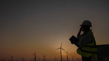 Kadın mühendis, Tayland 'daki dağda rüzgar türbini tarım güç jeneratörü istasyonunda çalışıyor ve raporu tutuyor.