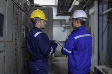 Elektrik mühendisleri ve teknisyenleri endüstriyel kontrol odalarındaki elektrik sistemi arızalarını çözmek için birlikte çalışıyorlar..