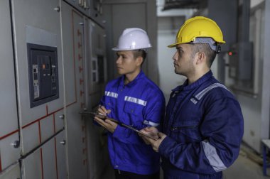 Elektrik mühendisleri ve teknisyenleri endüstriyel kontrol odalarındaki elektrik sistemi arızalarını çözmek için birlikte çalışıyorlar..