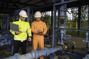 Mühendis ve teknisyen bakımı, su pompası ve basınç göstergesi, su tedarikçisinin teknik verilerini kontrol ediyor.