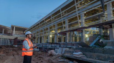Tayland 'da büyük bir inşaat projesinin şantiyesinde çalışan Asyalı mühendis inşaat alanında fazla mesai yapıyor.