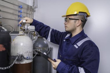 Tayland 'da, ameliyathanede çalışan Asyalı mühendis kask takıyor özenle ve sabırla çalışıyor, hidrojen tankının kapakçık düzenleyicisini kontrol ediyor..