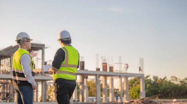 Tayland 'da büyük bir inşaat projesinin şantiyesinde çalışan iki Asyalı mühendis şantiyede fazla mesai, şantiyede çalışan bir mühendis diski.