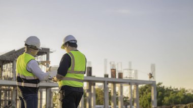 Tayland 'da büyük bir inşaat projesinin şantiyesinde çalışan iki Asyalı mühendis şantiyede fazla mesai, şantiyede çalışan bir mühendis diski.