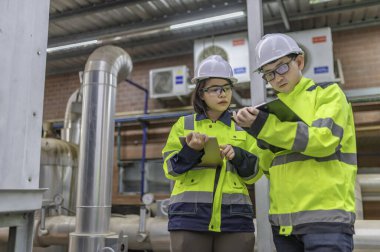 Bir ısıtma tesisinde bakım teknisyeni, Petrokimya işçileri fabrikadaki gaz ve petrol boru hatlarının işleyişini denetliyor, mühendisler işitme koruyucularını birçok boruyla aynı odaya koyuyorlar.