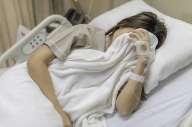 Asyalı kadın hasta ve hastanede tedavi görüyor, doktorun damar içi ilaç vermesini bekliyor, bir hemşire ateşimi ölçmek ve kan basıncımı ölçmek için geldi..