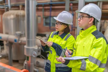 Bir ısıtma tesisinde bakım teknisyeni, Petrokimya işçileri fabrikadaki gaz ve petrol boru hatlarının işleyişini denetliyor, mühendisler işitme koruyucularını birçok boruyla aynı odaya koyuyorlar.