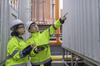 Bir ısıtma tesisinde bakım teknisyeni, Petrokimya işçileri fabrikadaki gaz ve petrol boru hatlarının işleyişini denetliyor, mühendisler işitme koruyucularını birçok boruyla aynı odaya koyuyorlar.