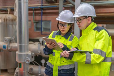 Bir ısıtma tesisinde bakım teknisyeni, Petrokimya işçileri fabrikadaki gaz ve petrol boru hatlarının işleyişini denetliyor, mühendisler işitme koruyucularını birçok boruyla aynı odaya koyuyorlar.