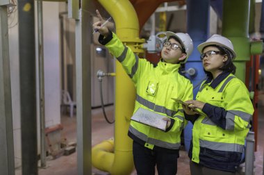 Bir ısıtma tesisinde bakım teknisyeni, Petrokimya işçileri fabrikadaki gaz ve petrol boru hatlarının işleyişini denetliyor, mühendisler işitme koruyucularını birçok boruyla aynı odaya koyuyorlar.