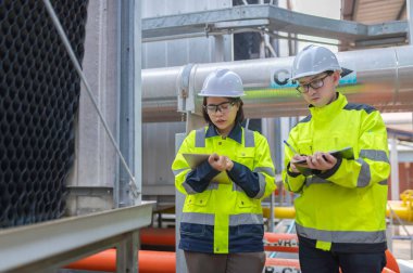 Bir ısıtma tesisinde bakım teknisyeni, Petrokimya işçileri fabrikadaki gaz ve petrol boru hatlarının işleyişini denetliyor, mühendisler işitme koruyucularını birçok boruyla aynı odaya koyuyorlar.