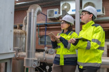 Bir ısıtma tesisinde bakım teknisyeni, Petrokimya işçileri fabrikadaki gaz ve petrol boru hatlarının işleyişini denetliyor, mühendisler işitme koruyucularını birçok boruyla aynı odaya koyuyorlar.
