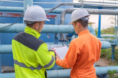 Mühendis ve teknisyen bakımı, su pompası ve basınç göstergesi, su tedarikçisinin teknik verilerini kontrol ediyor.