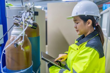 Tayland 'da, ameliyathanede çalışan Asyalı mühendis kask takıyor, özenle ve sabırla çalışıyor, hidrojen tankının valf düzenleyicisini kontrol ediyor..