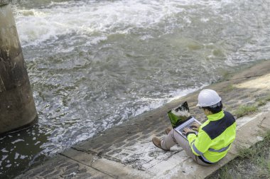 Kontrol rutinini yapan bir mühendis. Başlığı ve mühendis üniforması giyiyor. Demiryolunun kenarında duruyor. Birkaç gündür yağan şiddetli yağmurdan su seviyelerini izleyin..
