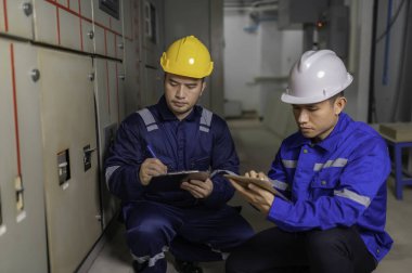 Elektrik mühendisleri ve teknisyenleri endüstriyel kontrol odalarındaki elektrik sistemi arızalarını çözmek için birlikte çalışıyorlar..