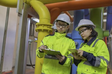 Bir ısıtma tesisinde bakım teknisyeni, Petrokimya işçileri fabrikadaki gaz ve petrol boru hatlarının işleyişini denetliyor, mühendisler işitme koruyucularını birçok boruyla aynı odaya koyuyorlar.