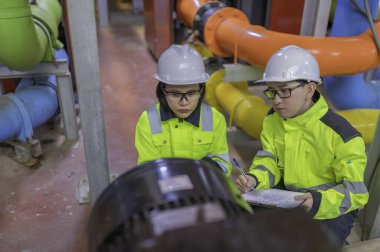 Bir ısıtma tesisinde bakım teknisyeni, Petrokimya işçileri fabrikadaki gaz ve petrol boru hatlarının işleyişini denetliyor, mühendisler işitme koruyucularını birçok boruyla aynı odaya koyuyorlar.
