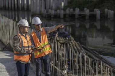 Nehir kıyısındaki bir köprü inşaatında inşaat mühendisi inşaat mühendisi, inşaat denetçisi, Foreman inşaat sahasında çalışıyor, teknik sorunları birlikte tartışıyorlar.