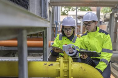 Bir ısıtma tesisinde bakım teknisyeni, Petrokimya işçileri fabrikadaki gaz ve petrol boru hatlarının işleyişini denetliyor, mühendisler işitme koruyucularını birçok boruyla aynı odaya koyuyorlar.