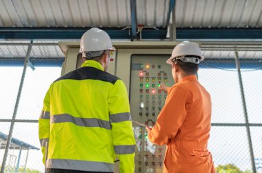 Elektrik mühendisi elektrik dağıtım kabinesinde voltajı kontrol ediyor, önleyici bakım yıllık, atık su arıtma tesisinde çalışan denetleyici