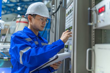 Electrical engineer woman checking voltage at the Power Distribution Cabinet in the control room,preventive maintenance Yearly,Thailand Electrician working at company