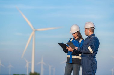 Tayland 'da, dağdaki rüzgar türbini çiftliği güç jeneratörü istasyonunda çalışan mühendisler ve çalışan mühendisler, teknisyen erkek ve kadın iş hakkında tartışıyorlar.