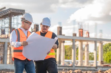 Tayland 'da büyük bir inşaat projesinin şantiyesinde çalışan iki Asyalı mühendis şantiyede fazla mesai, şantiyede çalışan bir mühendis diski.