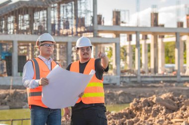 Tayland 'da büyük bir inşaat projesinin şantiyesinde çalışan iki Asyalı mühendis şantiyede fazla mesai, şantiyede çalışan bir mühendis diski.