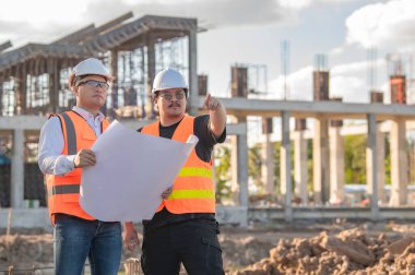 Tayland 'da büyük bir inşaat projesinin şantiyesinde çalışan iki Asyalı mühendis şantiyede fazla mesai, şantiyede çalışan bir mühendis diski.
