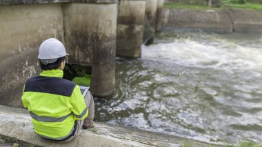 Kontrol rutinini yapan bir mühendis. Başlığı ve mühendis üniforması giyiyor. Demiryolunun kenarında duruyor. Birkaç gündür yağan şiddetli yağmurdan su seviyelerini izleyin..