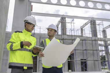 Büyük bir inşaat projesinin şantiyesinde çalışan iki Asyalı mühendis inşaat sahasında fazla mesai, inşaat alanında mühendislik diski.