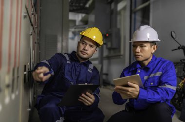 Elektrik mühendisleri ve teknisyenleri endüstriyel kontrol odalarındaki elektrik sistemi arızalarını çözmek için birlikte çalışıyorlar..