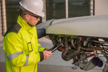 Teknisyen uçağın motorunu tamir ediyor, kadın uzay mühendisliği uçak motorlarını kontrol ediyor, Asyalı tamirci uçak motorlarını kontrol ediyor.