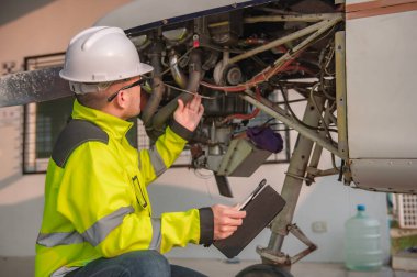 Teknisyen uçağın motorunu tamir ediyor, kadın uzay mühendisliği uçak motorlarını kontrol ediyor, Asyalı tamirci uçak motorlarını kontrol ediyor.