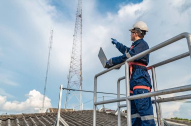 Engineer in Full Safety Gear Climbing a Ladder to Inspect Communication Signals and Industrial Machinery at a High-Risk Transportation Facility clipart