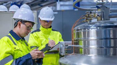 Tayland 'da, ameliyathanede çalışan Asyalı mühendis kask takıyor, özenle ve sabırla çalışıyor, hidrojen tankının valf düzenleyicisini kontrol ediyor..